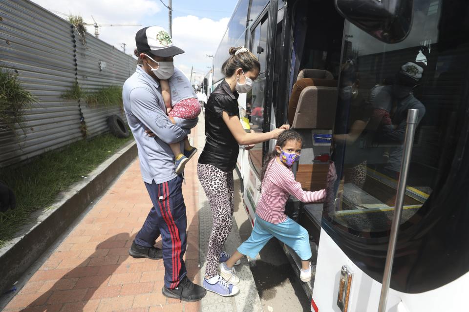 In this April 30, 2020 photo, Venezuelan migrants board a bus departing to the Venezuelan border amid the new coronavirus pandemic, in Bogota, Colombia. The Colombian government say it has paid for some of the bus trips to take the returning migrants to the Venezuelan border. (AP Photo/Fernando Vergara)