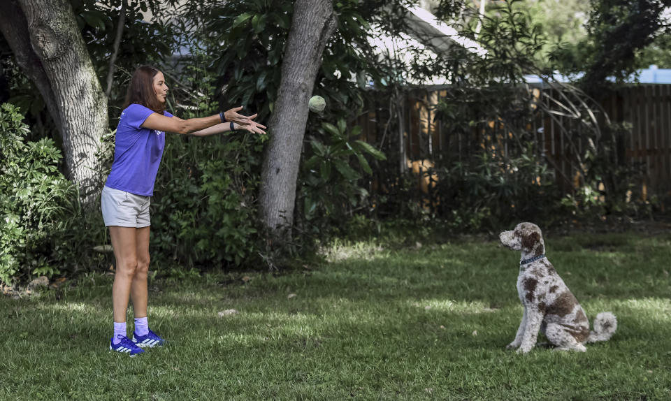 Michele Hall plays with her dog Beau in their backyard Thursday, June 24, 2021, in Bradenton, Fla. Hall, 54, diagnosed with early Alzheimer's last year, calls the new drug Aduhelm "the first tiny glimmer of hope" she'll get more quality time with her husband and their three adult children. (AP Photo/Steve Nesius)
