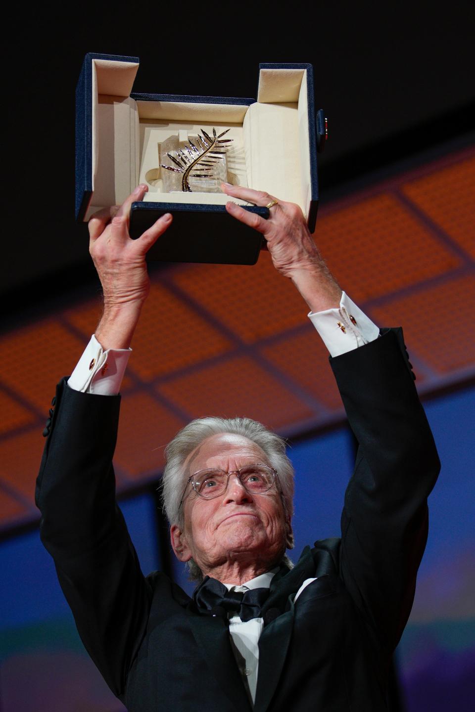 Michael Douglas holds his Honorary Palme d'Or in the air at the opening ceremony of the Cannes Film Festival.