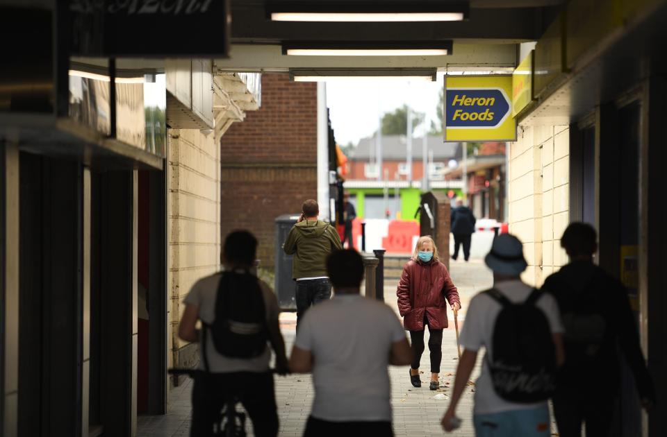 People wear face masks as a precaution against the transmission of COVID-19 as they walk past closed shops in the centre of Bolton, northern England on September 9, 2020, as local lockdown restrictions are put in place due to a spike in cases of the novel coronavirus in the city. - The UK government, which controls health policy in England, imposed tougher restrictions on Bolton, near the northwest city of Manchester, after a "very significant rise" in cases. Bolton was found to have 120 cases per 100,000 people -- the highest in the country. (Photo by Oli SCARFF / AFP) (Photo by OLI SCARFF/AFP via Getty Images)