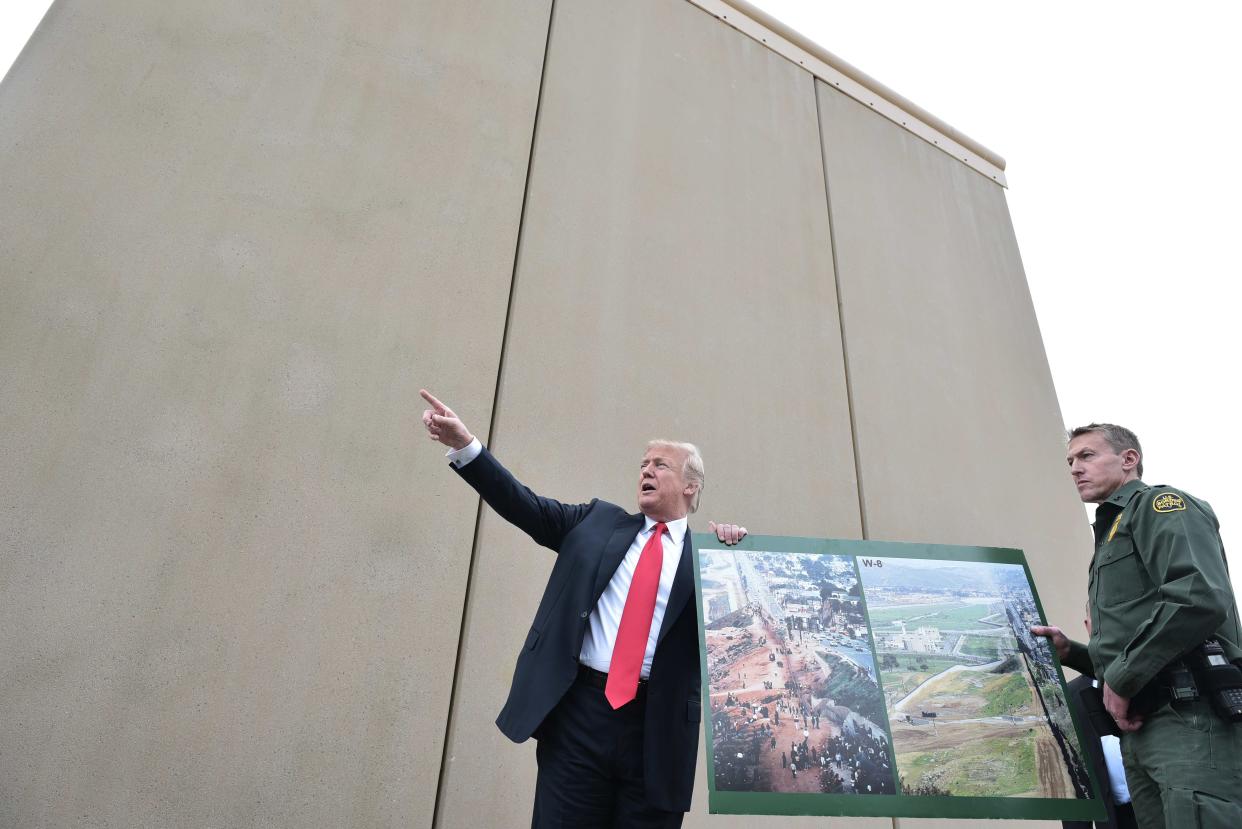 El presidente de EEUU, Donald Trump, sostiene un cartel junto a un prototipo del muro fronterizo que quiere construir, en San Diego, California, el 13 de marzo de 2018