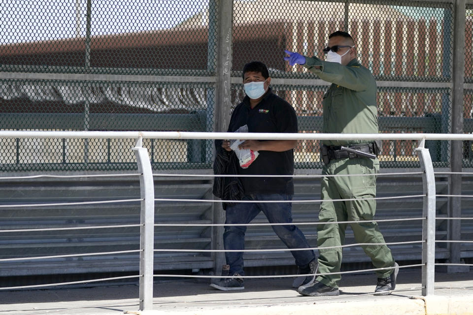 A U.S. Customs and Border Protection agent, right, leads a migrant, who was caught Thursday, March 18, 2021, in Hidalgo, Texas, trying to cross into the U.S., across the McAllen-Hidalgo International Bridge point of entry while being deported to Reynosa, Mexico. (AP Photo/Julio Cortez)