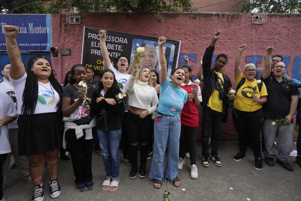 FILE - Students of the Thomazia Montoro public school shout for peace and against violence in front of a banner of Elisabete Tenreiro, a 71-year-old teacher who was stabbed to death the previous day, during a vigil at their school in Sao Paulo, Brazil, March 28, 2023. Brazil is grappling with a wave of violence in its schools. The government has sought input from independent researchers and convened a meeting on Tuesday, April 18, 2023, of ministers, mayors and Supreme Court justices to discuss possible solutions. (AP Photo/Andre Penner, File)