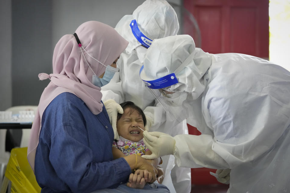 A medical worker collects swab sample from a child during coronavirus testing at a COVID-19 testing center in Shah Alam, outskirts of Kuala Lumpur, Malaysia, Thursday, May 27, 2021. Malaysia's latest coronavirus surge has been taking a turn for the worse as surging numbers and deaths have caused alarm among health officials, while cemeteries in the capital are dealing with an increasing number of deaths. (AP Photo/Vincent Thian)