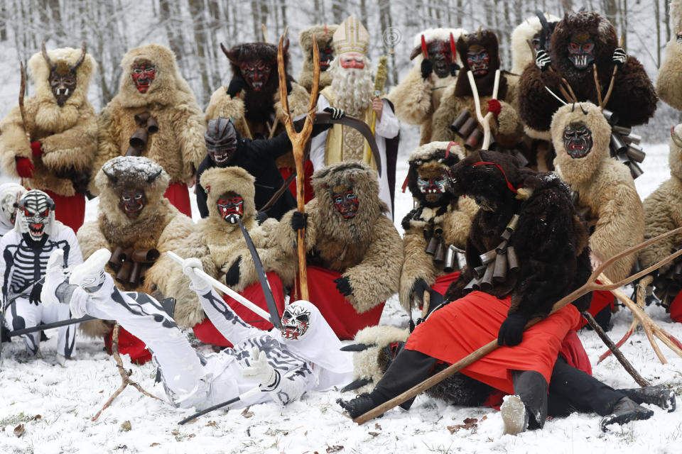 Revelers depicting grim reapers and devils pose for a photo during a traditional St Nicholas procession in the village of Valasska Polanka, Czech Republic, Saturday, Dec. 7, 2019. This pre-Christmas tradition has survived for centuries in a few villages in the eastern part of the country. The whole group parades through village for the weekend, going from door to door. St.Nicholas presents the kids with sweets. The devils wearing home made masks of sheep skin and the white creatures representing death with scythes frighten them. (AP Photo/Petr David Josek)