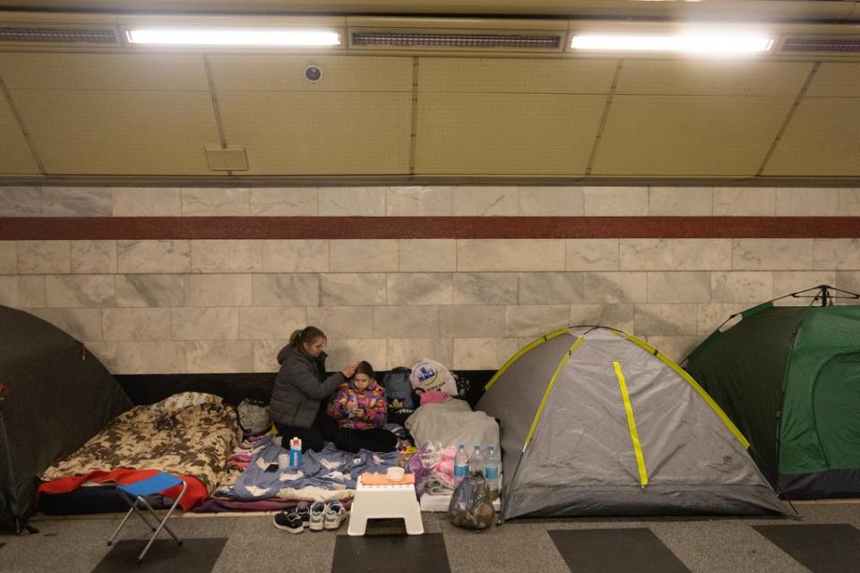 A woman sheltering in a Kyiv metro station brushes her daughters hair (Getty Images)