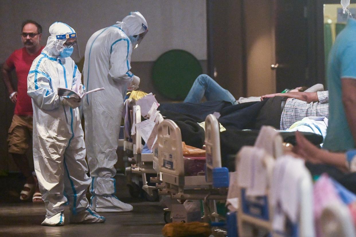 <p>Health workers attend to patients inside a banquet hall temporarily converted into a Covid-19 ward in Delhi on 1 May, 2021</p> (AFP via Getty Images)