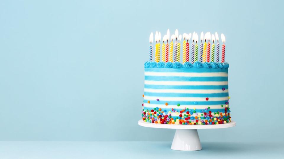 striped turquoise birthday cake with colorful birthday candles and sprinkles