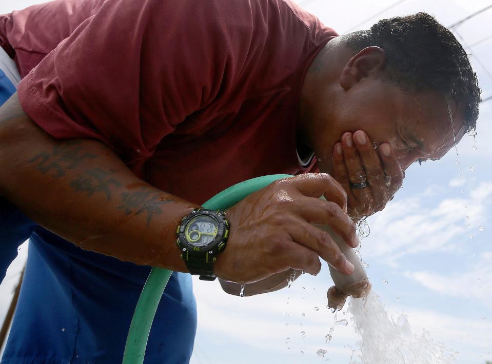 Micole Felder cools off with some water at a car wash as temperatures soared to 110 degrees on July 12, 2019, in Phoenix.