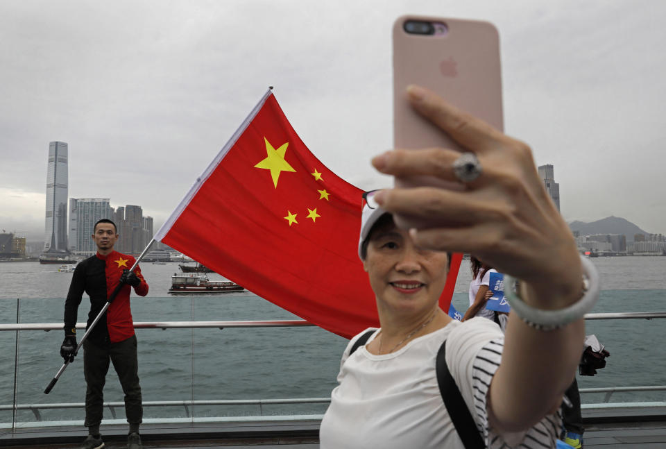 FILE - In this Saturday, Aug. 17, 2019, file photo, pro-China supporters take a selfie with a Chinese national flag to support police and anti-violence during a rally at a park in Hong Kong. A year after Beijing imposed a harsh national security law on Hong Kong, the civil liberties that raised hopes for more democracy are fading. (AP Photo/Vincent Yu, File)