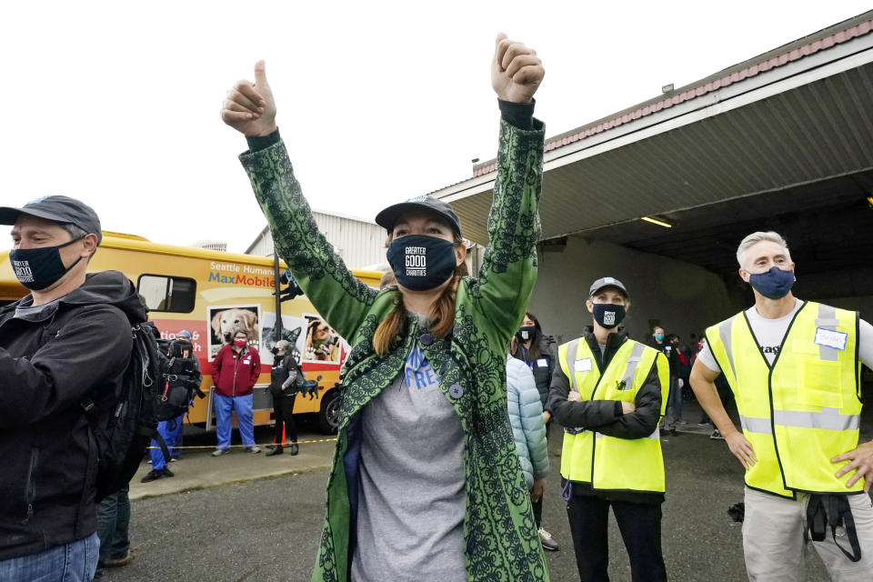 Liz Baker, CEO of Greater Good Charities, raisers her arms as she watches the landing of a "Paws Across the Pacific" pet rescue flight Thursday, Oct. 29, 2020, in Seattle. Volunteer organizations flew more than 600 dogs and cats from shelters across Hawaii to the U.S. mainland, calling it the largest pet rescue ever. The animals are being taken from overcrowded facilities in the islands to shelters in Washington state, Oregon, Idaho, and Montana. (AP Photo/Elaine Thompson)