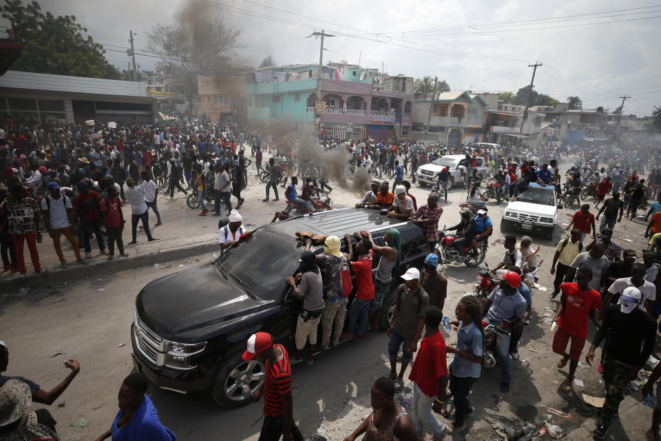 Demonstrators hang from an SUV during a protest calling for the resignation of President Jovenel Moise, in Port-au-Prince, Haiti, Friday, Oct. 4, 2019. After a two-day respite from the recent protests that have wracked Haiti's capital, opposition leaders urged citizens angry over corruption, gas shortages, and inflation to join them for a massive protest march to the local headquarters of the United Nations.(AP Photo/Rebecca Blackwell)