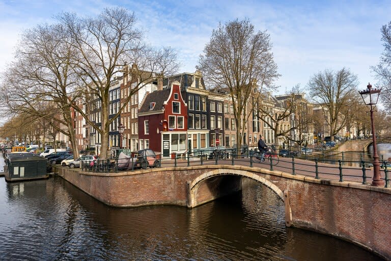 Un ciclista cruza un puente sobre un canal en el centro histórico de Ámsterdam el 26 de marzo de 2021