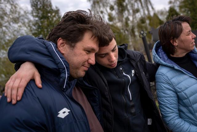 Yura Nechyporenko, 15, hugs his uncle Andriy Nechyporenko next to the grave of his father Ruslan Nechyporenko at the cemetery in Bucha, on the outskirts of Kyiv, Ukraine, on Monday, April 25, 2022. The teen survived an attempted killing by Russian soldiers while his father was killed, and now his family seeks justice.