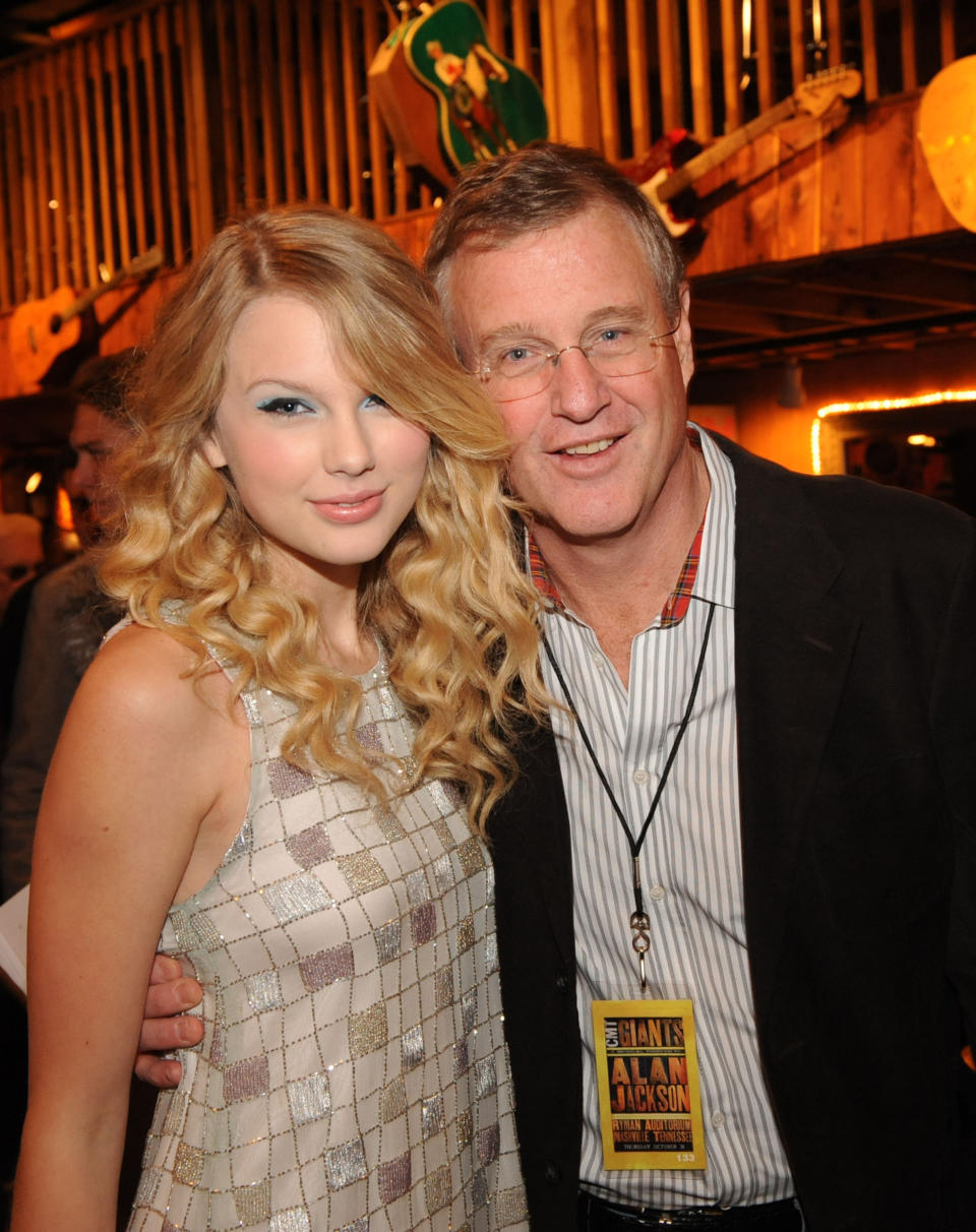 Taylor Swift in a patterned dress with Scott Swift wearing eyeglasses and a lanyard