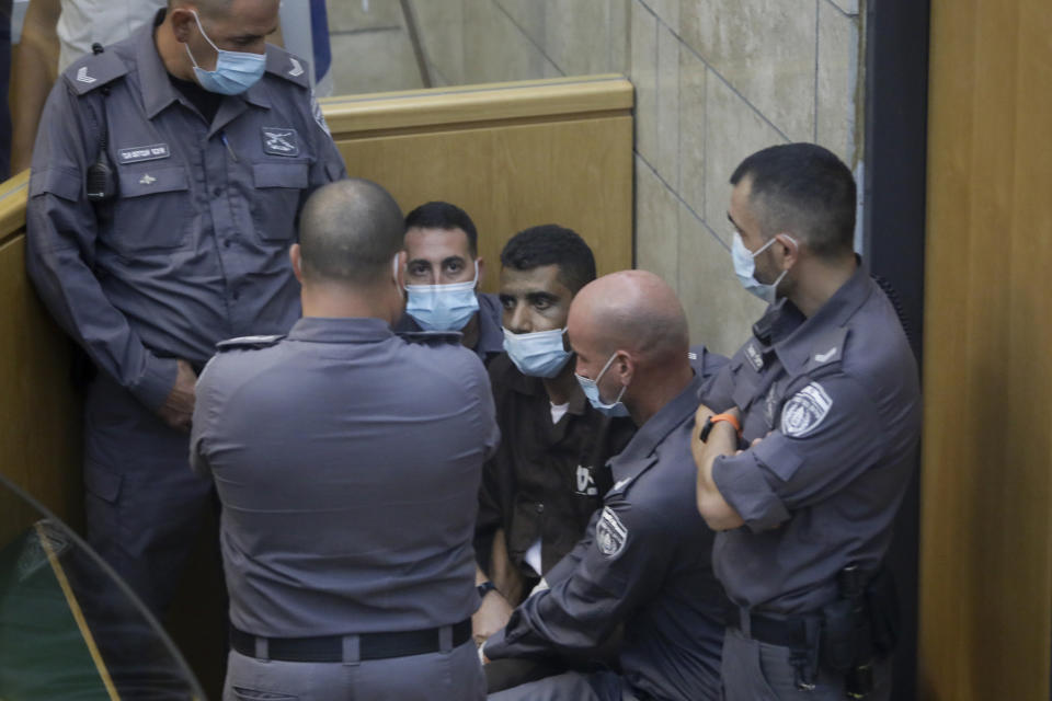 Zakaria Zubeidi, one of the six Palestinians who escaped from a high-security prison earlier this week is surrounded by guards as they stand in a courtroom in Nazareth, Israel, after he and three other Palestinian fugitives were captured on Saturday, Sept. 11, 2021. Israeli police on Saturday said they have arrested four of the six Palestinians who broke out of a maximum-security prison this week including Zubeidi a famed militant leader whose exploits over the years have made him a well-known figure in Israel. (AP Photo/Sebastian Scheiner)