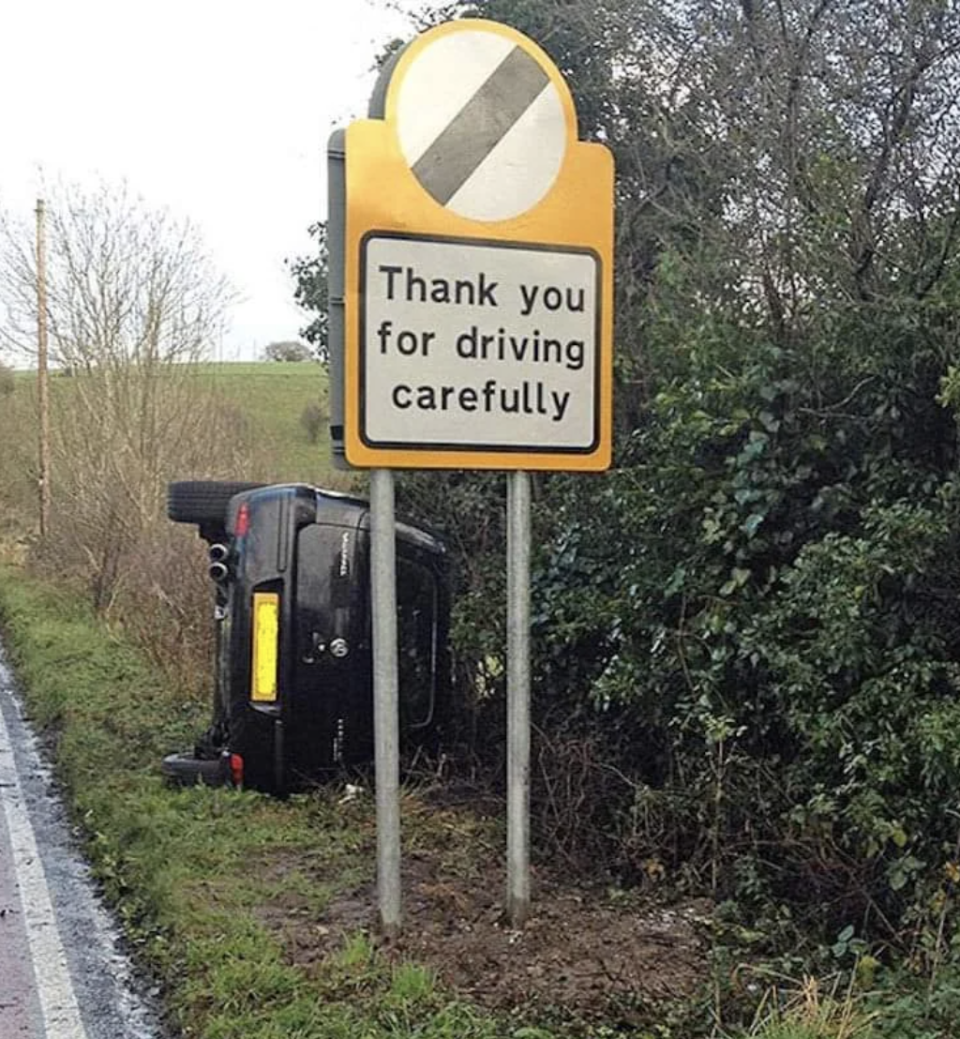 Sign reads "Thank you for driving carefully" next to an overturned car off the road