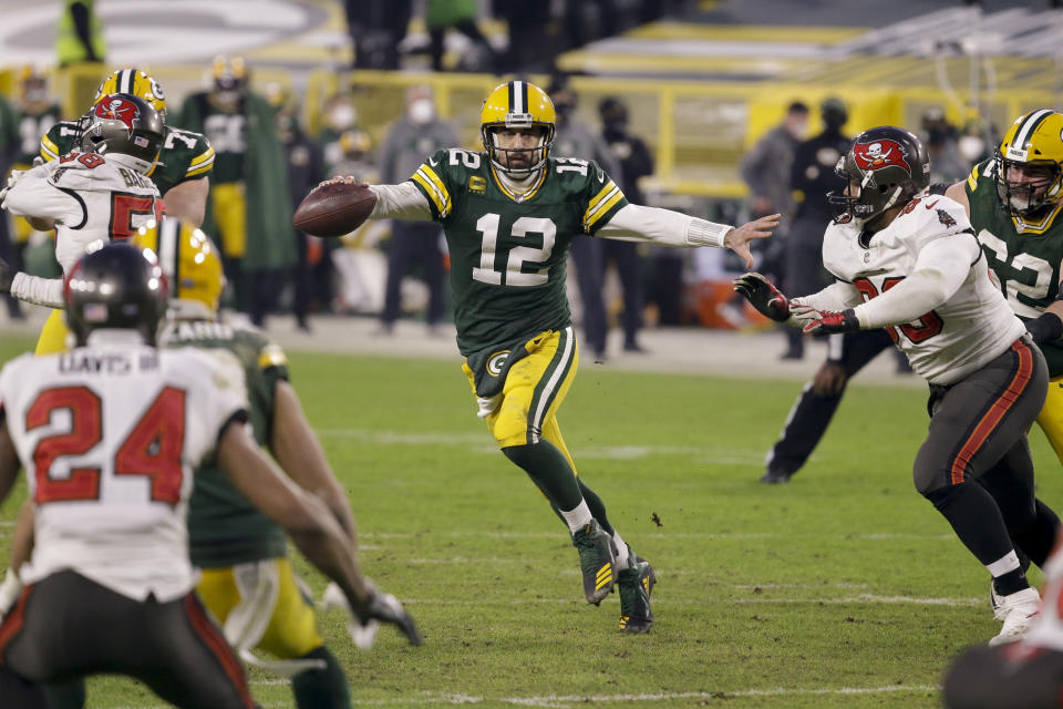 Green Bay Packers quarterback Aaron Rodgers (12) evades a tackle as he looks to pass against the Tampa Bay Buccaneers during the second half of the NFC championship NFL football game in Green Bay, Wis., Sunday, Jan. 24, 2021. (AP Photo/Mike Roemer)