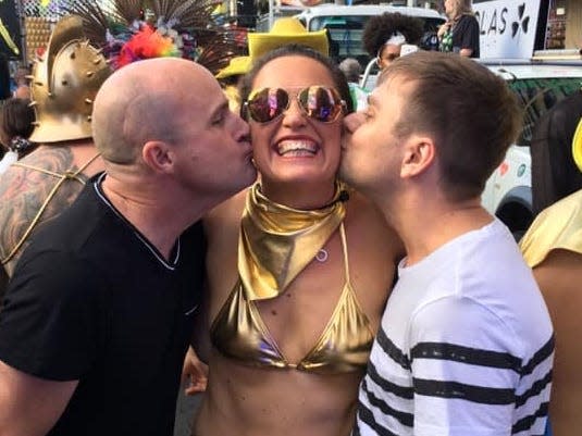 Teresa Leggett at mardi gras getting kissed by two men on each cheek