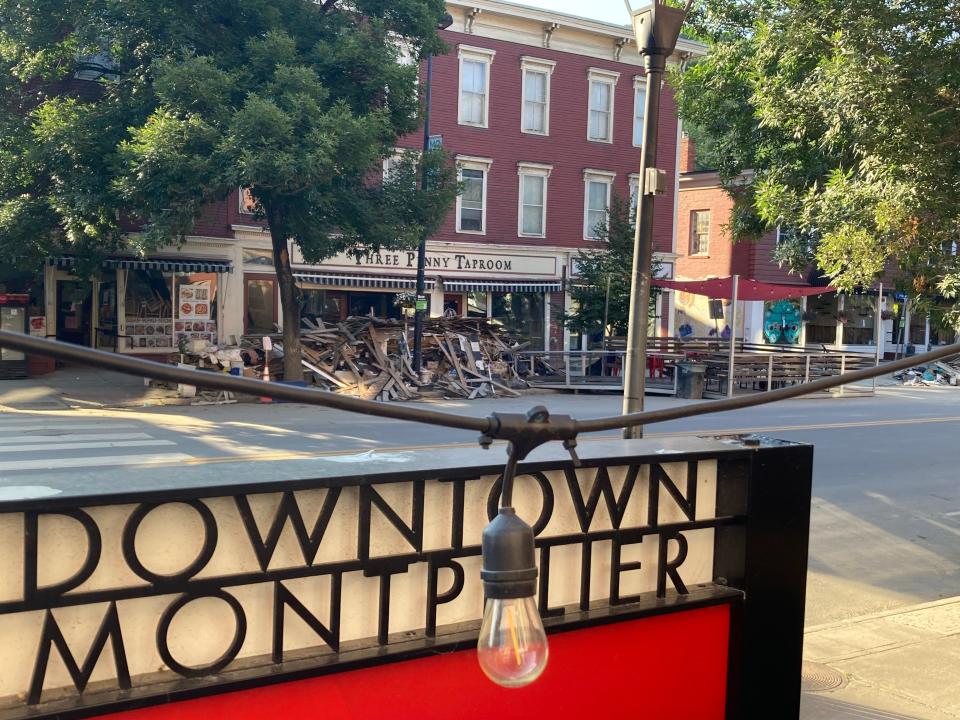Debris remains piled up July 20, 2023 in front of the Three Penny Taproom, as seen from the patio outside The Skinny Pancake on Main Street, more than a week after devastating floods hit Montpelier.