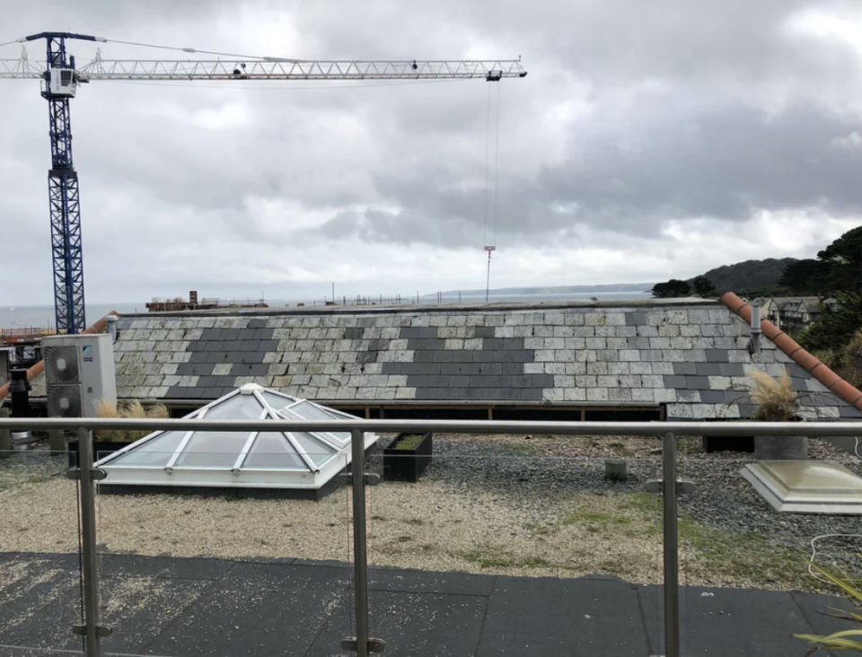 The sea view blocked by the top of a brick and stone roof