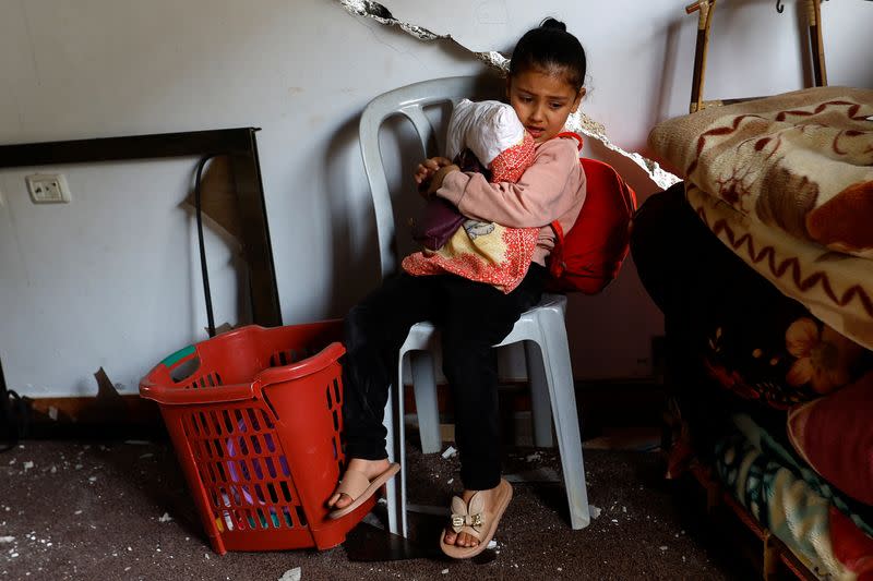 Palestinian girl sits inside her house which was destroyed in Israeli air strikes, in Deir al-Balah town