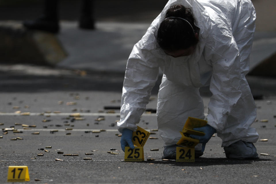 A forensic investigator tags cartridges at the scene where the Mexican capital's police chief was attacked by gunmen in Mexico City, Friday, June 26, 2020. Heavily armed gunmen attacked and wounded Omar GarcÌa Harfuch in an operation that left several dead. (AP Photo/Rebecca Blackwell)