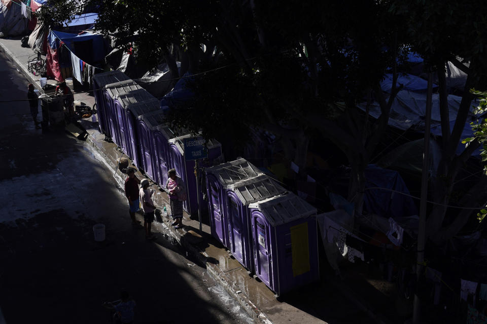 Migrants talk in front of portable toilets in a camp in Tijuana, Mexico, on Nov. 8. (Gregory Bull / AP file)