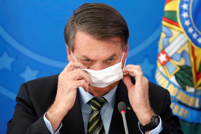 Brazil's President Jair Bolsonaro adjusts his protective face mask during a news conference to announce measures to curb the spread of the coronavirus disease (COVID-19) in Brasilia