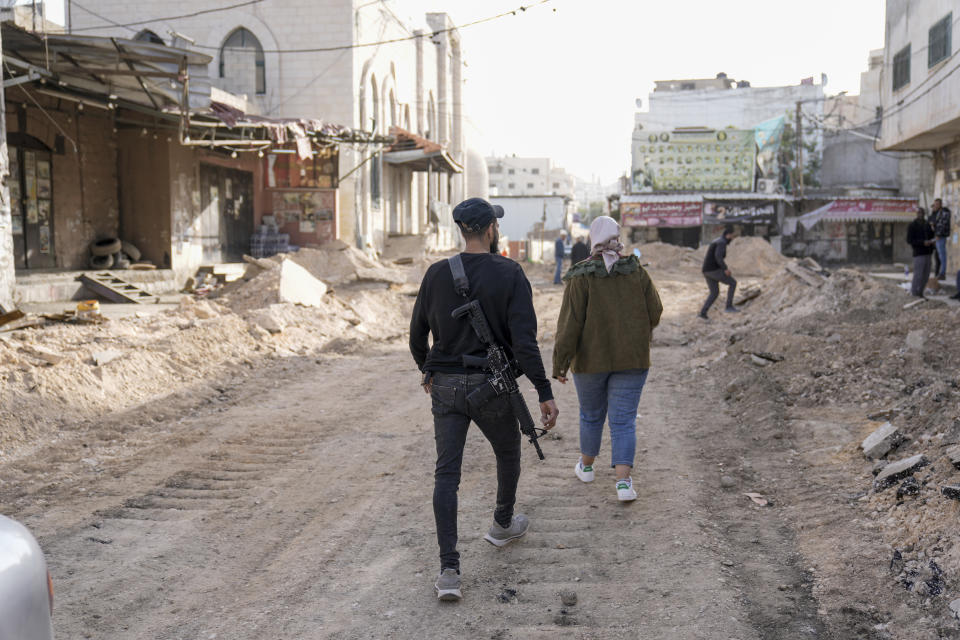 A Palestinians gunman walks on a damaged road following an Israeli army operation in Jenin refugee camp, West Bank, Sunday, Nov. 26, 2023. Israeli forces operating in the occupied West Bank killed at least eight Palestinians in a 24-hour period, Palestinian health officials said Sunday. (AP Photo/Majdi Mohammed)