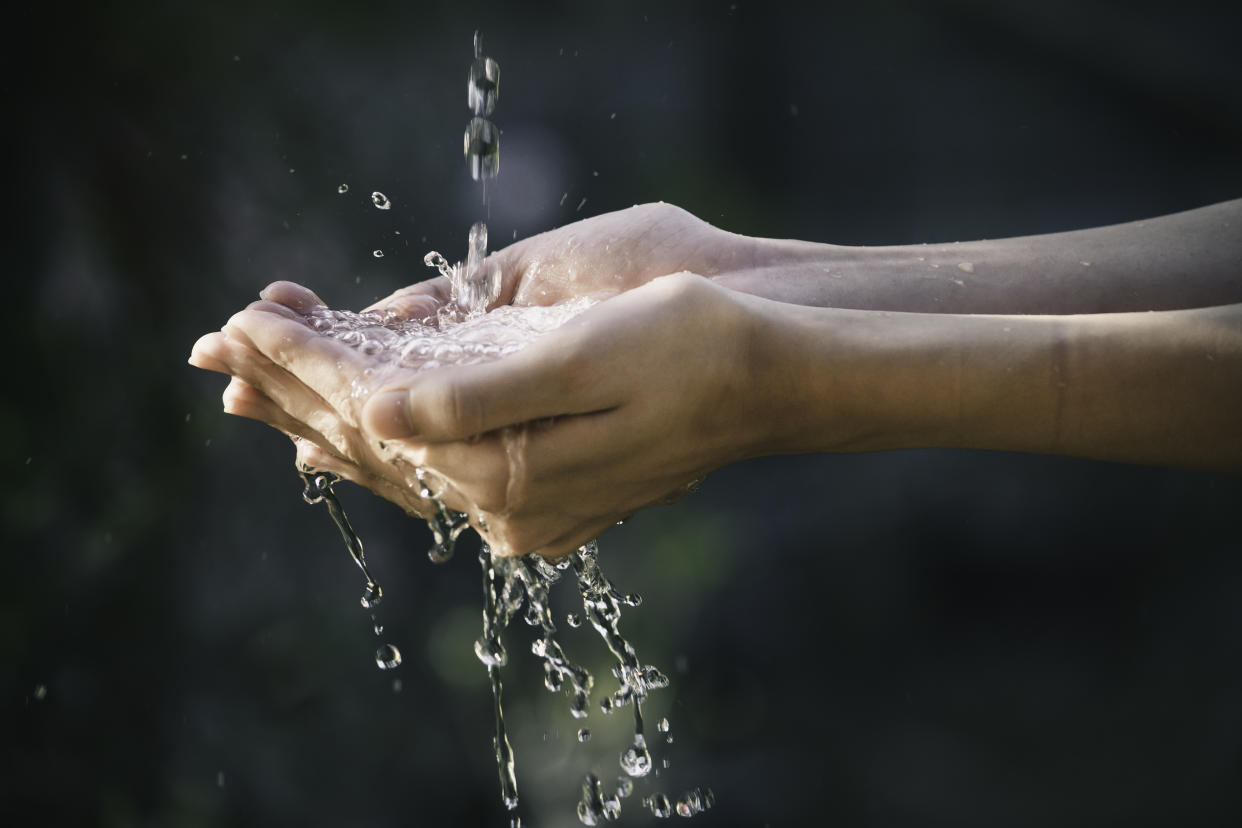 closeup water flow to hand of women for nature concept on the garden background. (Getty Images)