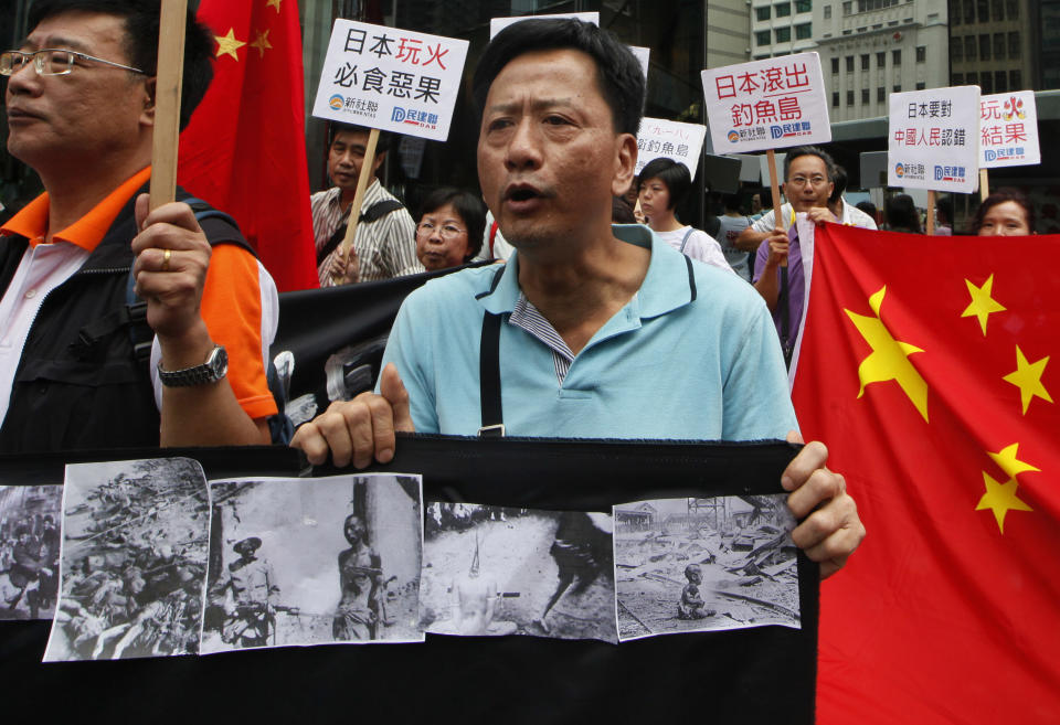 Anti-Japan protesters show pictures taken during a Japanese invasion of China outside the Japanese Consulate General in Hong Kong Tuesday, Sept. 18, 2012. The 81st anniversary of a Japanese invasion brought a fresh wave of anti-Japan demonstrations in China on Tuesday, with thousands of protesters venting anger over the colonial past and a current dispute involving contested islands in the East China Sea. (AP Photo/Kin Cheung)