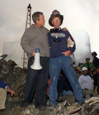 President George W. Bush embraces firefighter Bob Beckwith while standing in front of the collapsed World Trade Center buildings in New York on September 14, 2001. (AP Photo/Doug Mills)