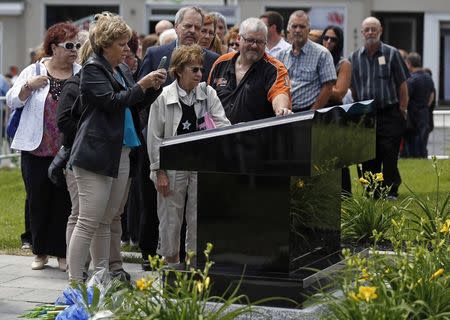 People take pictures of a memorial monument after a memorial mass at the Sainte-Agnes church in Lac-Megantic, July 6, 2014. REUTERS/Mathieu Belanger