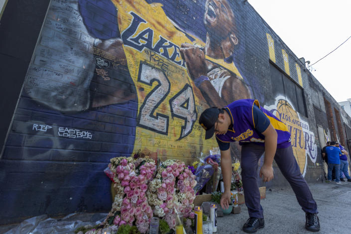 A man places a candle near a mural for former Los Angeles Lakers basketball star Kobe Bryant during the official memorial ceremony for him and his daughter, Gianna, at nearby Staple Center on February 24, 2020 in Los Angeles, California.