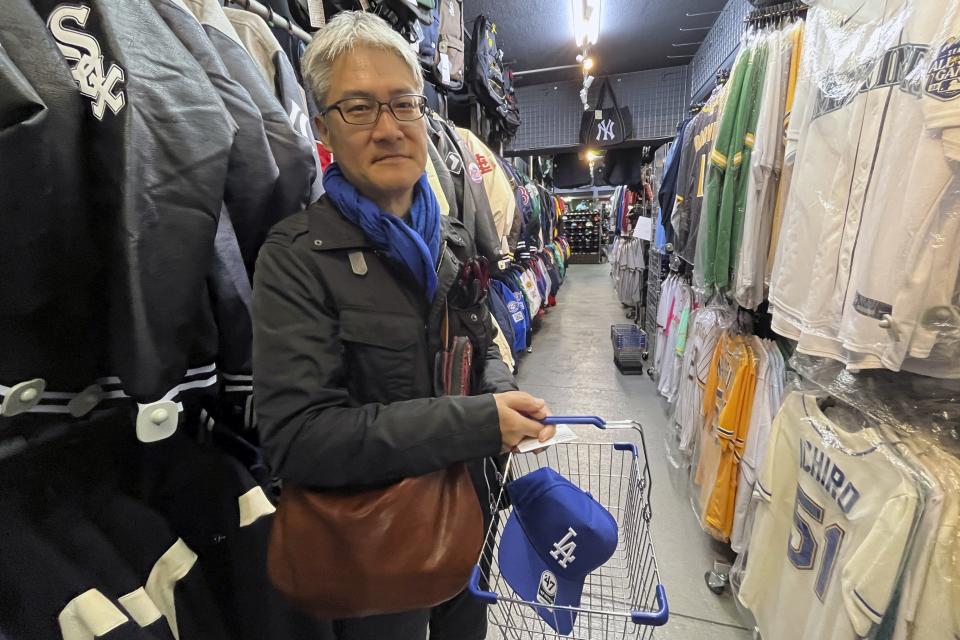 Hideki Chiba has a blue Dodgers cap in his basket, a gift for his father-in-law, as he shops on Monday Feb 26, 2024, at a sporting goods store, "SELECTION," in Shinjuku district in Tokyo. (AP Photo/Stephen Wade)