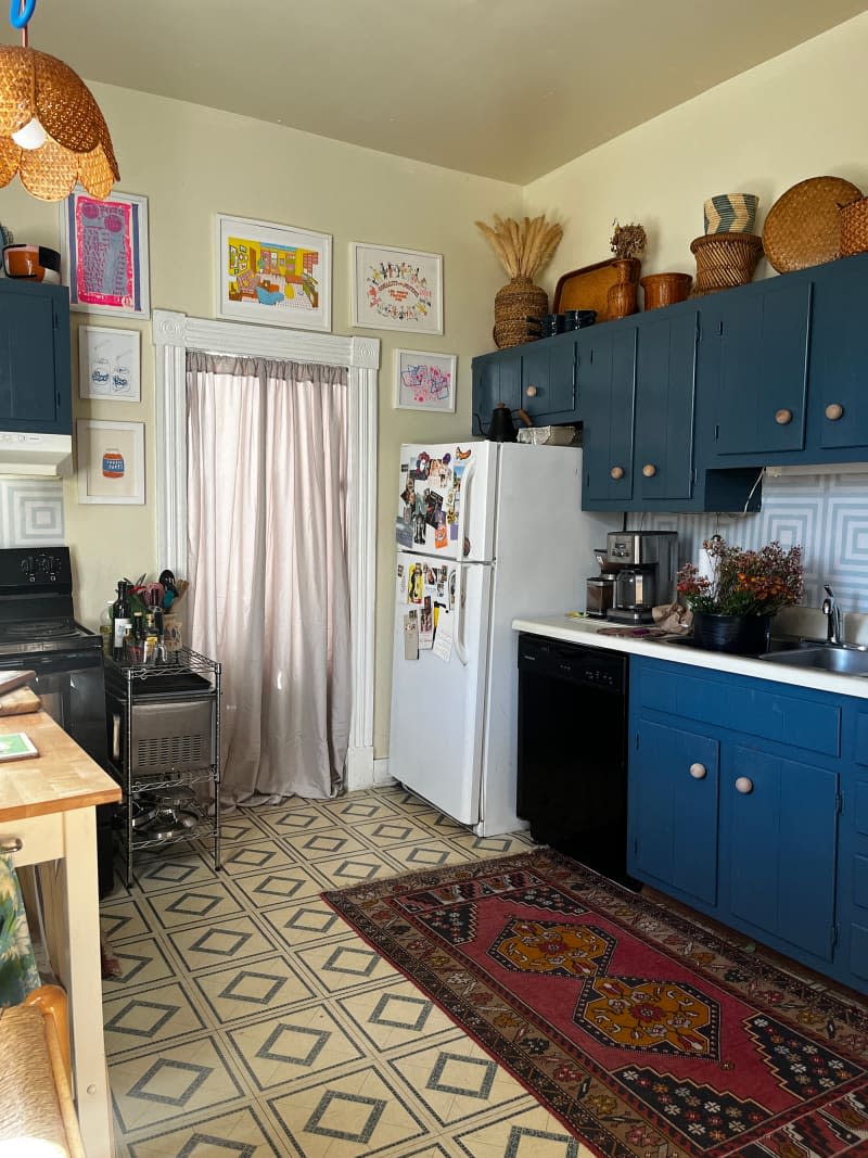 Curtain separates pale yellow kitchen with blue cabinetry and tiled floor.