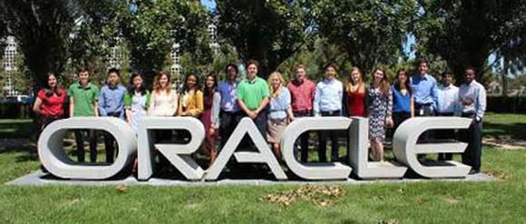 Picture of several Oracle employees standing outside behind its logo.
