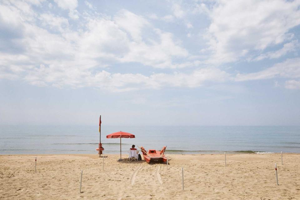 A red umbrella and a boat on the beach in Gaeta, Italy