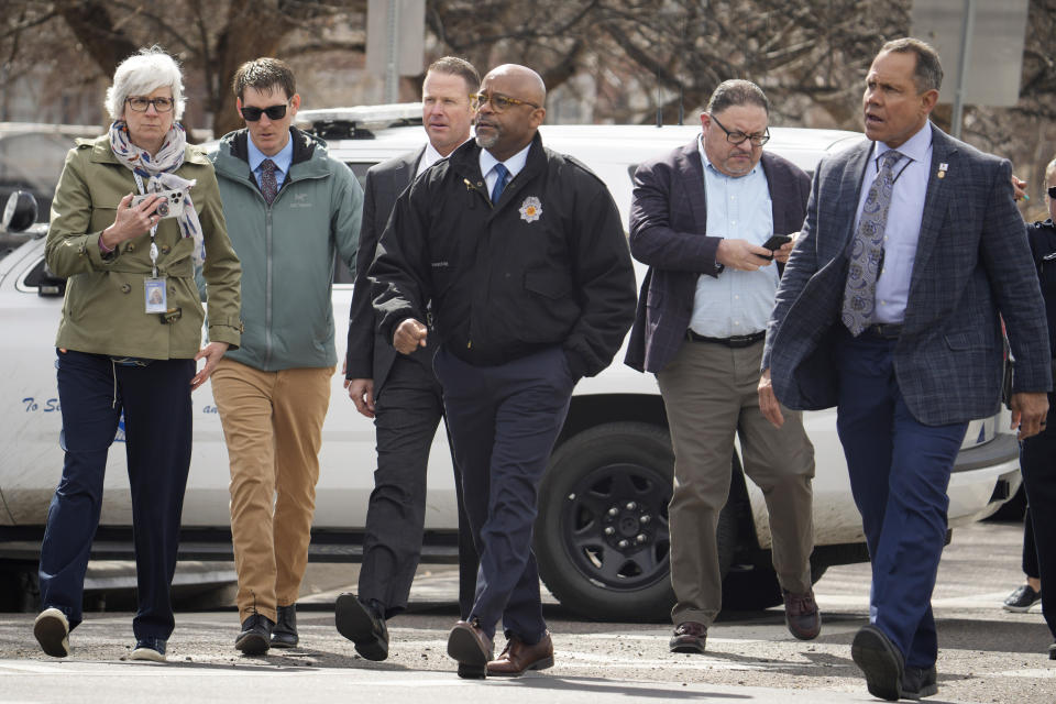 Denver Mayor Michael Hancock, center, walks across 17th Avenue to talk to parents as they wait for their children to be walked out of East High School after a school shooting Wednesday, March 22, 2023, in Denver. (AP Photo/David Zalubowski)