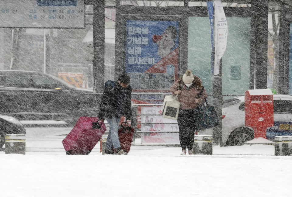People head to a bus station amid heavy snowfall in Gwangju, South Korea, Tuesday, Jan. 24, 2023. Thousands of travelers swarmed a small airport in South Korea's Jeju island on Wednesday in a scramble to get on flights following delays by snowstorms as frigid winter weather gripped East Asia for the second straight day. (Chun Jung-in/Yonhap via AP)