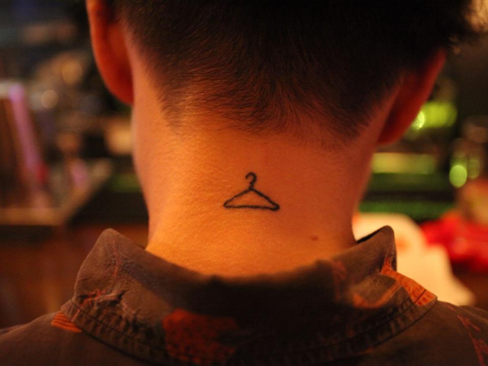 A woman with a tiny hanger tattoo on her neck