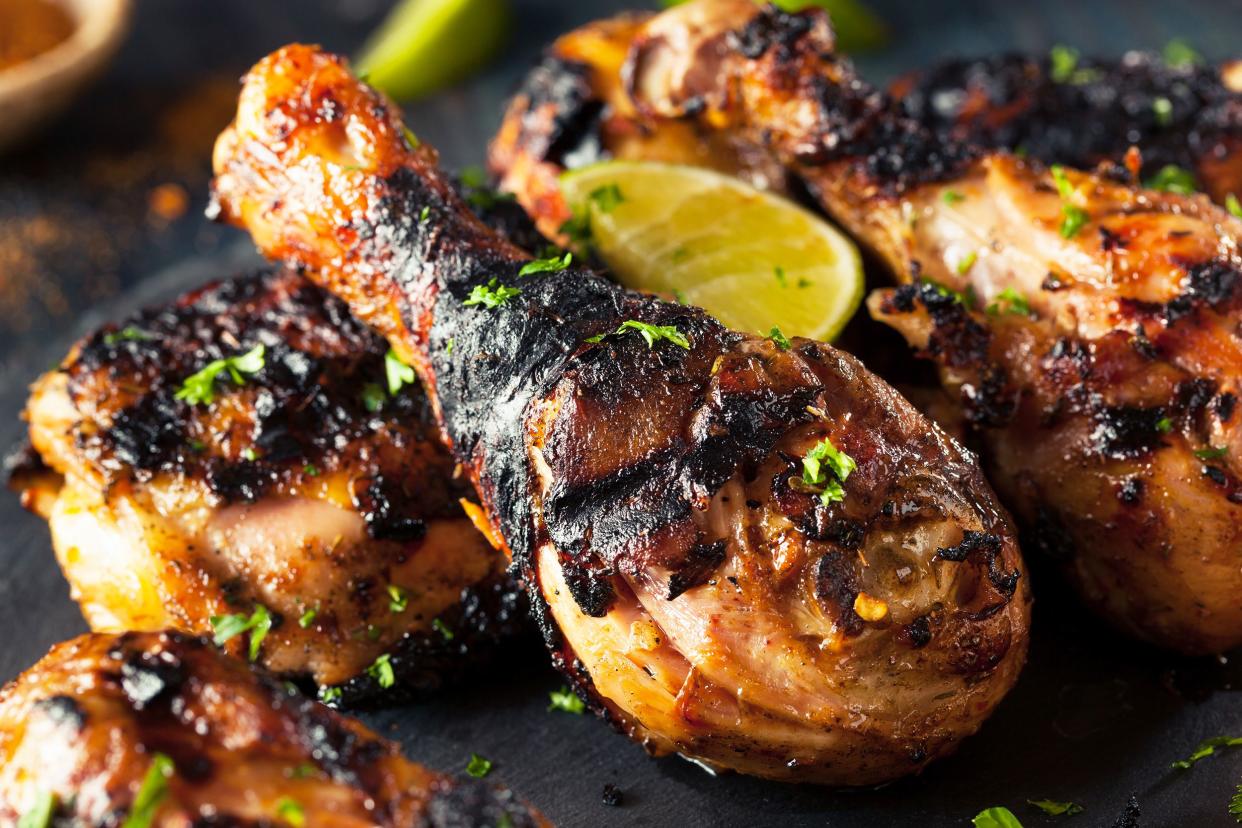 Closeup of many slow cooker jerk chicken drumsticks with a dark blurred background