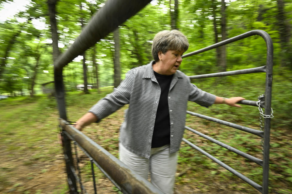 Pam Butler walks her property that borders a massive Jack Daniels barrelhouse complex, Wednesday, June 14, 2023, in Mulberry, Tenn. A destructive and unsightly black fungus which feeds on ethanol emitted by whiskey barrels has been found growing on her property and others near the barrelhouses. (AP Photo/John Amis)