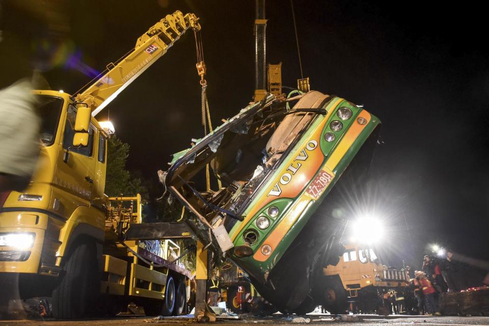 In this photo released by Xinhua News Agency, the wreckage of a crashed tourist bus is lifted on a highway in Taipei, Taiwan Tuesday, Feb. 14, 2017. The bus carrying Taiwanese tourists on a trip to view cherry blossoms flipped over on an expressway ramp in Taiwan's capital on Monday, killing more than 30 people and injuring many others, officials said. (Ou Dongqu/Xinhua via AP)