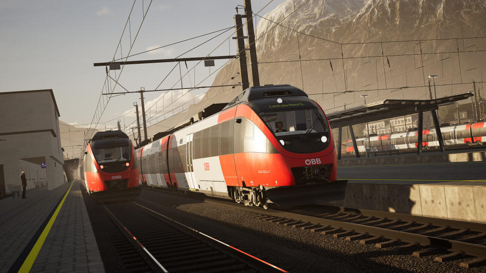 Two trains heading toward the direction of the camera with a mountain behind.