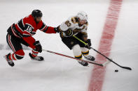 Boston Bruins left wing Brad Marchand (63) moves the puck ahead of Chicago Blackhawks left wing Jujhar Khaira (16) during the first period of an NHL hockey game, Saturday, Nov. 19, 2022, in Boston. (AP Photo/Mary Schwalm)