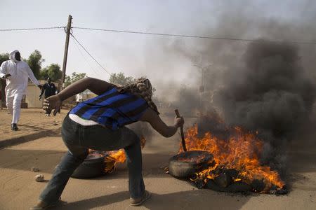 A man burns a tire during a protest against Niger President Mahamadou Issoufou's attendance last week at a Paris rally in support of French satirical weekly Charlie Hebdo, which featured a cartoon of the Prophet Mohammad as the cover of its first edition since an attack by Islamist gunmen, in Niamey January 17, 2015. REUTERS/Tagaza Djibo