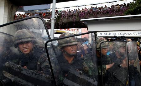 Soldiers hold their shields as they pull back after objects are thrown at them by protestors against military rule at Victory Monument in Bangkok May 28, 2014. REUTERS/Erik De Castro