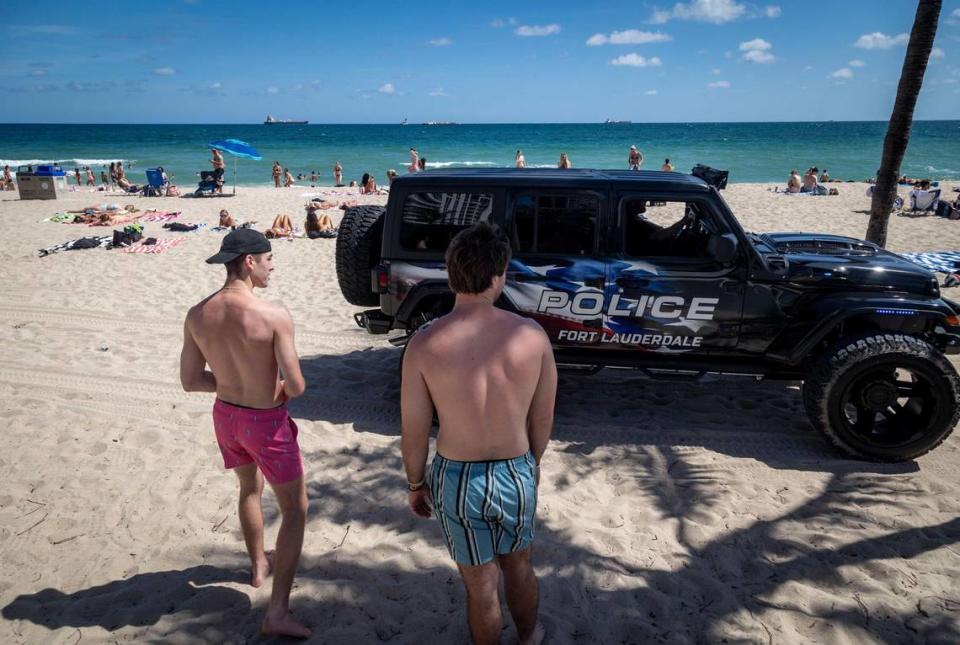 Dos 'spring breakers' originarios de Michigan ceden el paso a un vehículo de la policía de Fort Lauderdale en la arena de Fort Lauderdale Beach, el 28 de febrero de 2024.